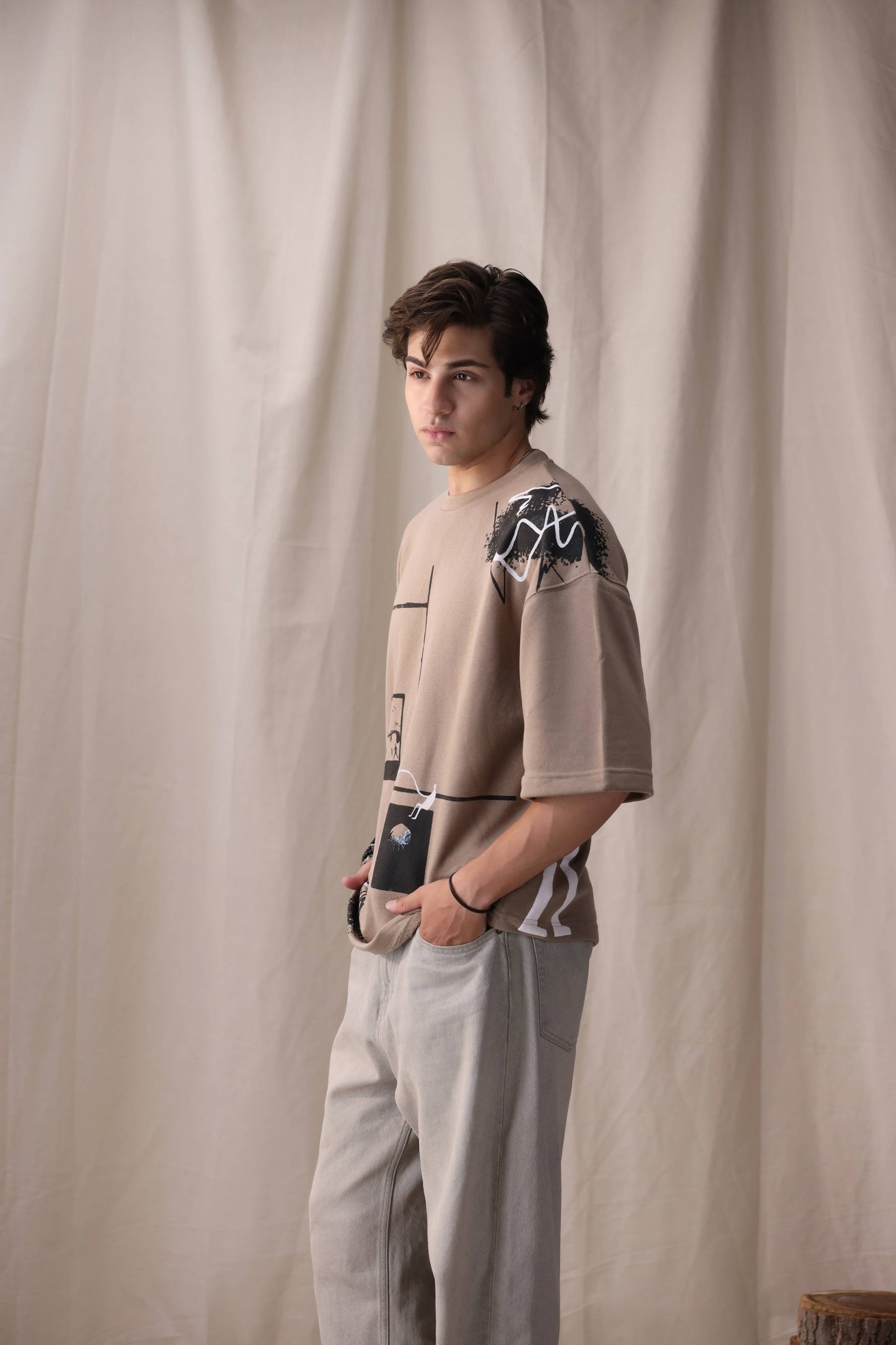 Model wearing Rukn beige oversized box fit unisex t-shirt by Shatrnj