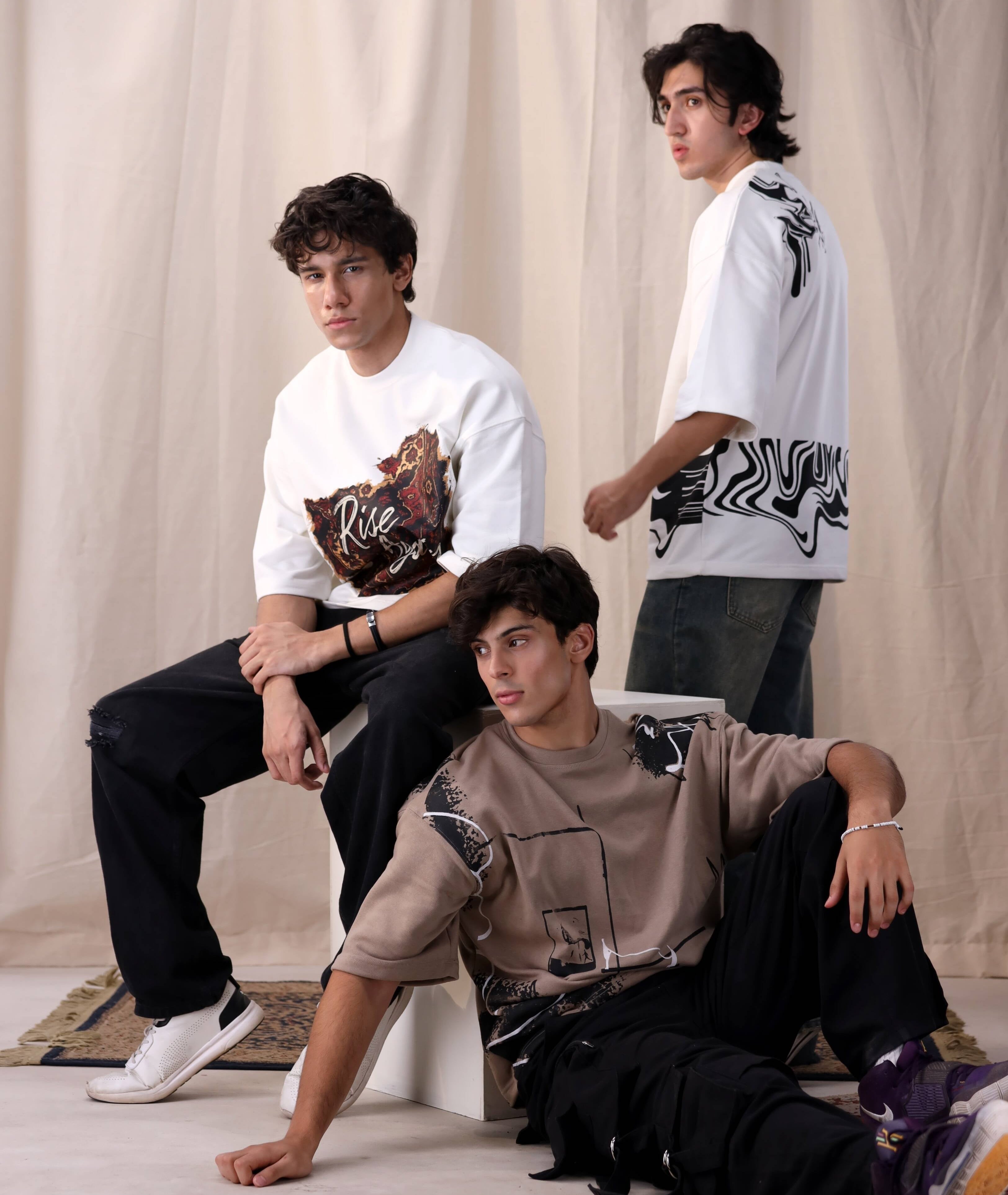 Three individuals posing against a plain background wearing stylish clothing.